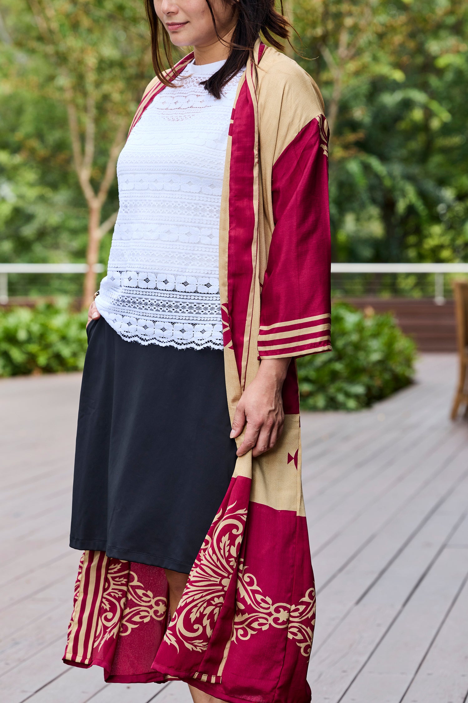 Woman wearing a boho chic maroon and beige printed upcycled sari gown over a white crochet lace top and black skort