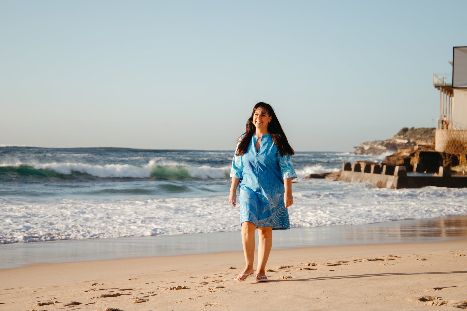 Woman walking on the beach wearing an ocean waves swimwear cover up dress